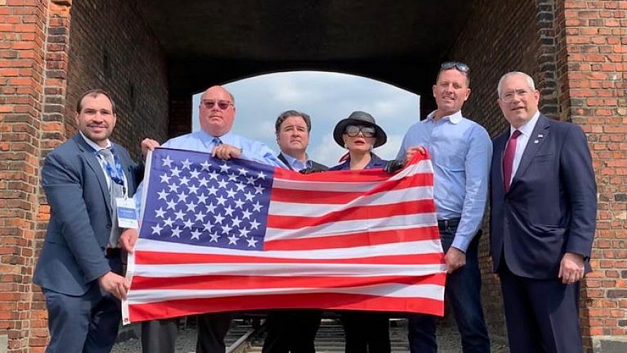 Members of the first-ever official U.S. government delegation to the March of the Living hold the American flag up at the Auschwitz-Birkenau concentration camps in Poland on May 2, 2019. Credit: March of the Living.